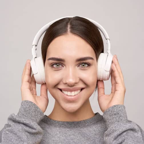 Smiling woman enjoying music with white headphones
